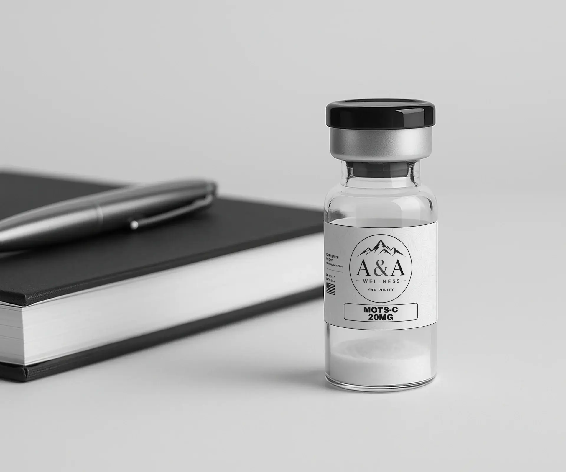 Black notebook, silver pen and an A&A Wellness research vial on a clean white desk