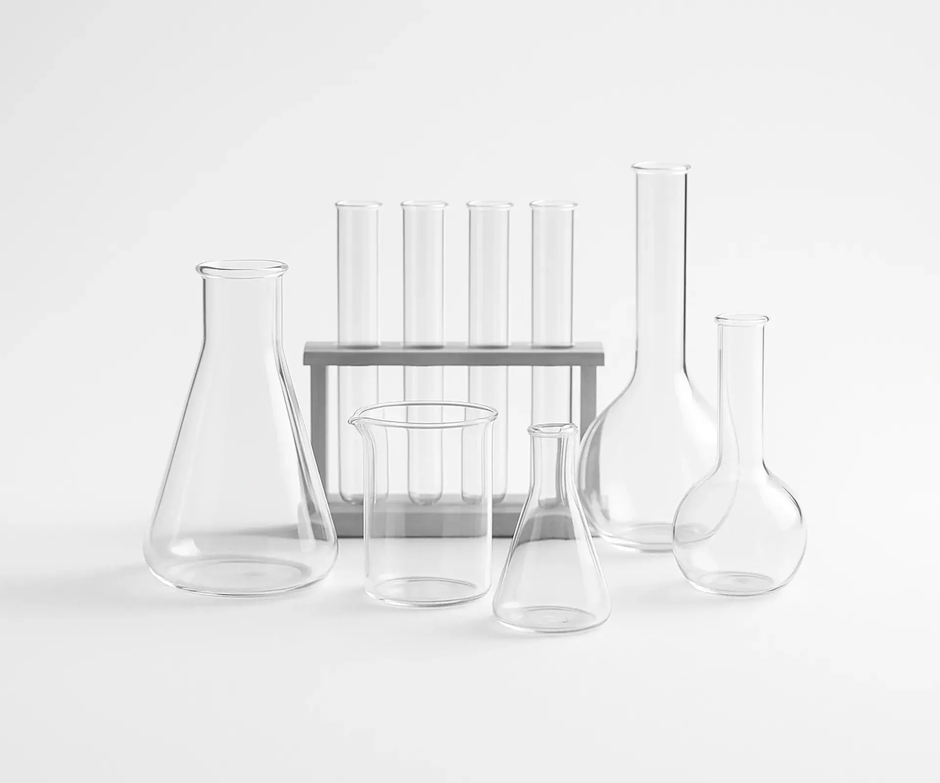 Arrangement of clear laboratory glassware, flasks, beakers and test tubes, on a white bench