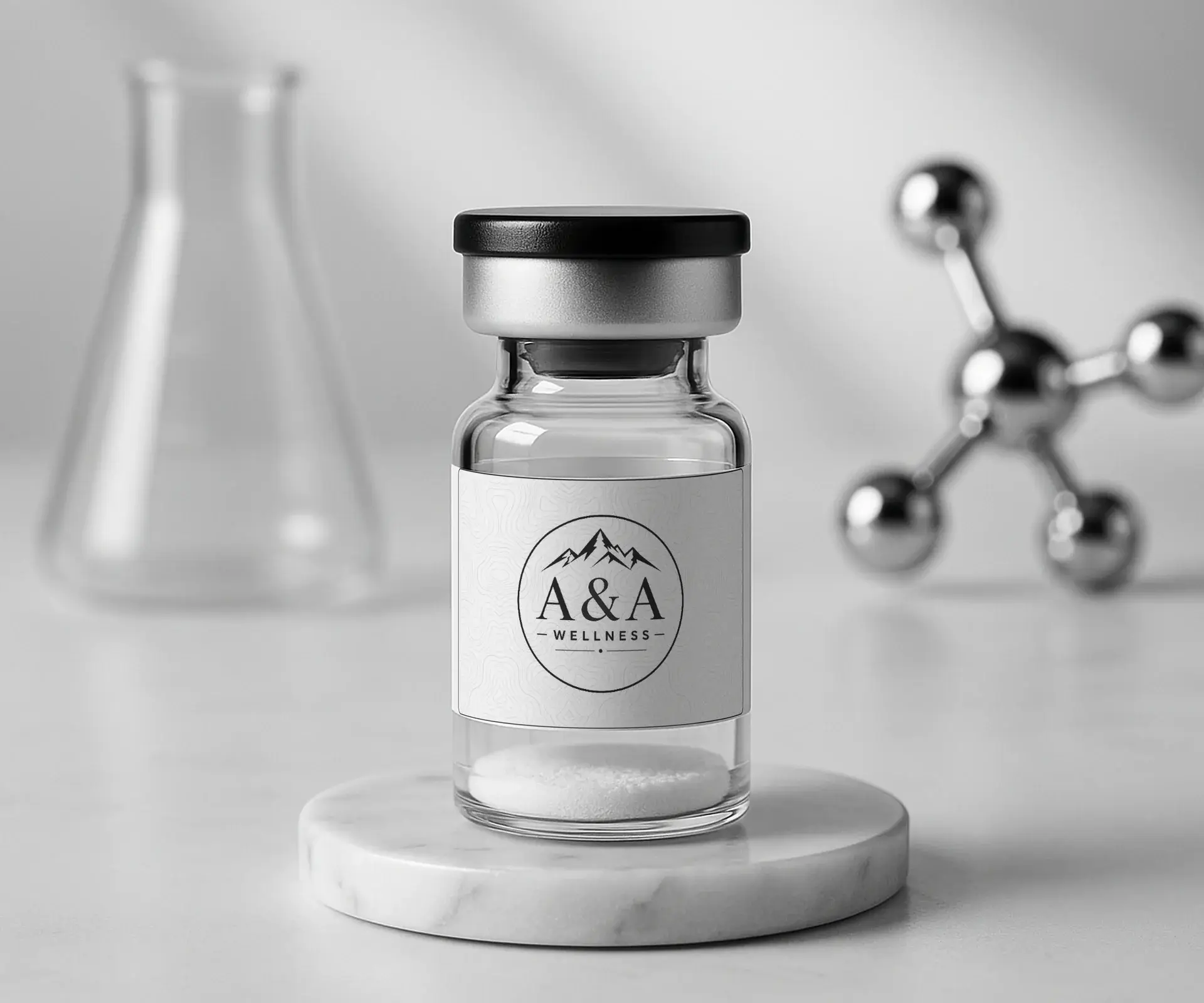 A single A&A Wellness research vial on a round white marble riser with a glass flask and chrome molecule model in the background