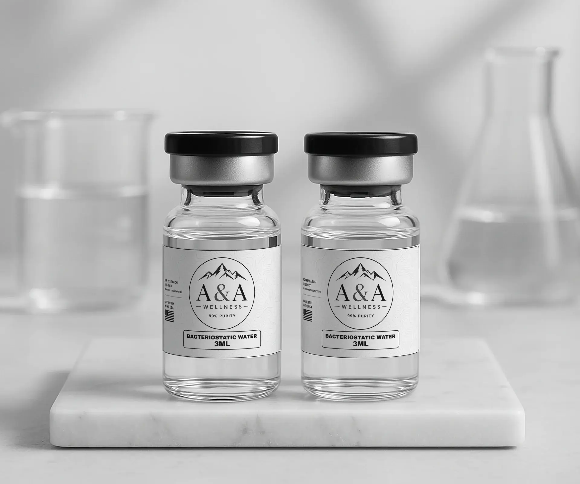 Two A&A Wellness bacteriostatic water 3mL vials on a white marble riser with a glass beaker and flask in the background